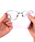 Eyeglasses with metal frame being wiped by white microfiber cloth