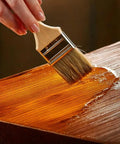 Top Shelf 100 Percent Pure Linseed Oil Wood Finish And Protective Sealer For Indoor Outdoor Furniture Plus Hardwood Surfaces Deeply Absorbs To Beat Sun And Rain Wear Keeping Grains Smooth And Radiant 32 Ounce Can being applied with a brush on wood.