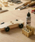 Copper Pinewood Derby Weights Kit Must Have With Three Sizes One Quarter Ounce One Eighth Ounce One Sixteenth Ounce Four Point Five Ounces Plus Graphite Powder Lubricant Anti Tarnish Coated For Derby Car Wheels And Axles, showing wooden derby car with weights and lubricant bottle on a table.
