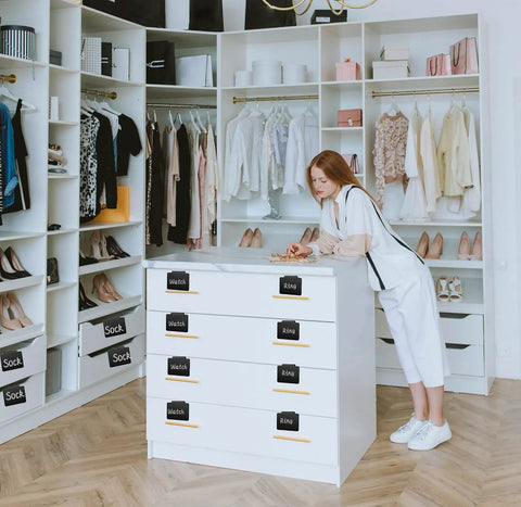 Woman organizing closet with Ultimate 81 Piece Basket Label Kit With Clip On Labels for clothing and accessories.