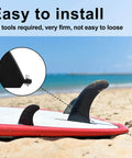 Close-up of a surfboard fin installed with 6 Piece No Tool Stainless Steel Thumb Fin Screws For Surfboard Longboard Paddleboard And SUP 316 Stainless Replacement Fin Hardware For Men And Women Easy Install Plug And Play Durable Corrosion Resistant Fin Screws on sandy beach.