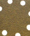 Close-up of the surface of a 5 inch hook and loop sanding disc, featuring aluminum oxide grit texture and holes for dust extraction. Get The 150 Pack Of High Performance 5 Inch Hook And Loop Sanding Discs With Versatile Aluminum Oxide Grits For Smoother Orbital Sander Projects That Fly Off Clogging And Hold Tough.