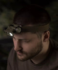 Man wearing Sidewinder 55 Lumen Compact II Military Flashlight with headstrap, hands free on helmet or molle gear, coyote color