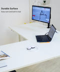 Badass Electric Sit To Stand L Shaped Corner Desk With Smooth Height Adjustment, Spacious 78 By 60 Inch Work Surface with laptop and monitor on white surface.