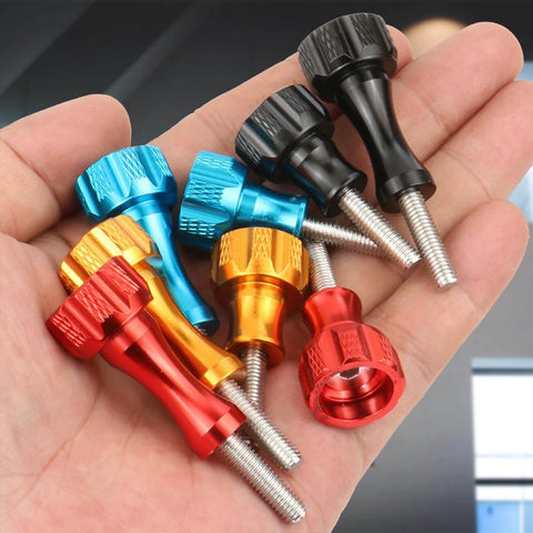 Hand holding multicolored CNC machined aluminum thumb screws for action cameras, compatible with Hero and Insta360 standard mounts.
