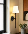 KSANA Modern Black Wall Scone Lighting Indoor with White Fabric Shade mounted beside a window, featuring a slender profile.