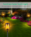 Lit Solar Flame Torch Lights For Outdoors With 99 LED Flickering Flames 43 Inch Waterproof Pathway Lights Solar Powered Backyard Garden Patio Lighting Four Pack installed in garden