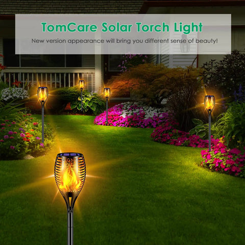 Lit Solar Flame Torch Lights For Outdoors With 99 LED Flickering Flames 43 Inch Waterproof Pathway Lights Solar Powered Backyard Garden Patio Lighting Four Pack installed in garden