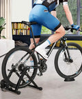Person using Magnetic Indoor Bike Trainer Stand With Front Wheel Support And Quick Release Skewer in a living room setting.