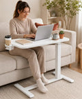 Mobile Rolling Desk Featuring Hidden Wheels And Smooth Pneumatic Height Adjustment Portable Laptop Stand For Home Office Or Bedside Setup Lightweight White Surface with a user working.