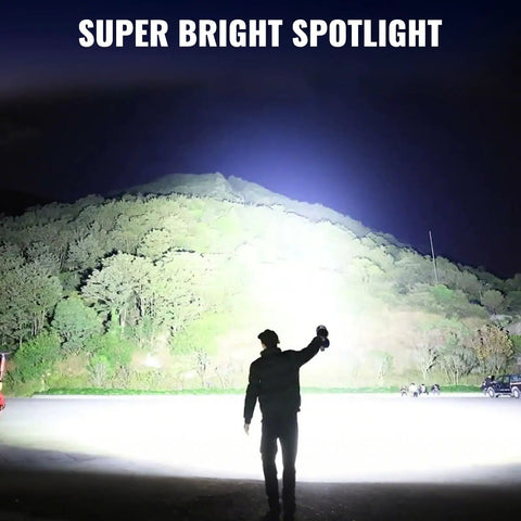Person using Rechargeable Spotlight 2 Million Lumens Handheld Searchlight With Solar Panels For Boating Camping Hunting And Power Outages Long Range 2000 Meter Beam Beastly Bright LED Spotlight For Outdoor Emergencies illuminating a hillside at night