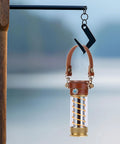 Camping Light Strap Set Carrier Portable Hand Lamp Belt with brown PU leather strap hanging on hook outdoors.