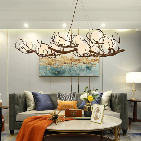 Sleek Vintage Moon Led Chandelier Boasts Natural Branch Silhouette And Nine Soft Glowing Fixtures to enhance living space over a stylish sofa.
