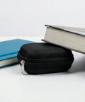 Hearing Aid Case With Travel Pouch And Battery Holder next to books, showcasing compact black EVA shell, waterproof storage.