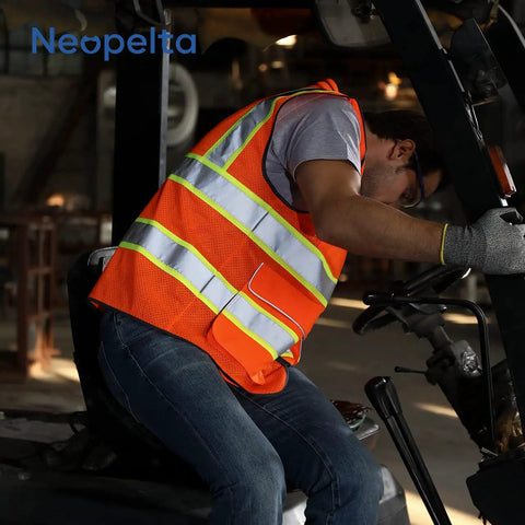 Heavy Duty Hi Vis Reflective Safety Vest For Men And Women Class Two High Visibility Work Vest With Badass Durability and Super Comfy Padded Collar For Job Sites, worn by a worker operating a forklift.