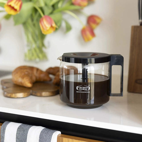 1.25L Glass Carafe for KBG Brewers, Clear Black Version, resting on kitchen counter next to croissants, holds 40 ounces of coffee