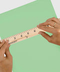 Go To 36 Inch Wood Yardstick With Dual Sided Scales And Clear Lacquer Finish held over green paper for measurement