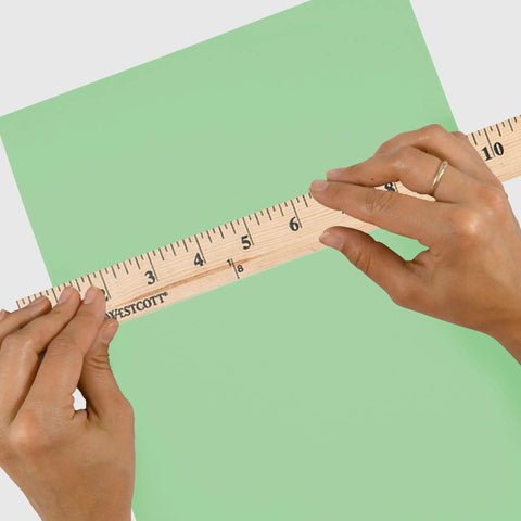 Go To 36 Inch Wood Yardstick With Dual Sided Scales And Clear Lacquer Finish held over green paper for measurement