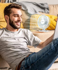 Man sitting with smiling expression next to Compact USB Desk Fan Tiny But Mighty On The Go Personal Table Fan With 3 Speed Settings