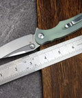 Fast Opening Ball Bearing Folding Knife With Pocket Clip D2 Steel Blade G10 Handle shown next to a ruler on wood surface.
