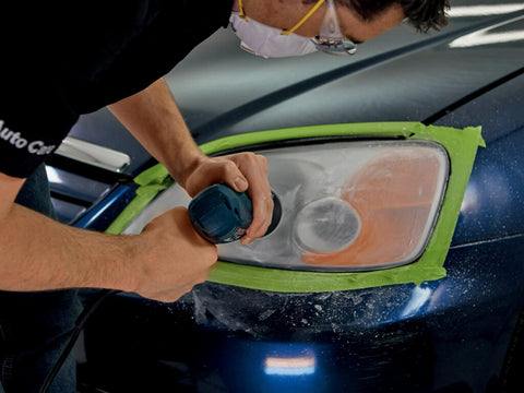 Man using Ultra Headlight Restoration Kit With Masking Tape Sanding Discs Finishing Discs Refining Disc Wax on headlight