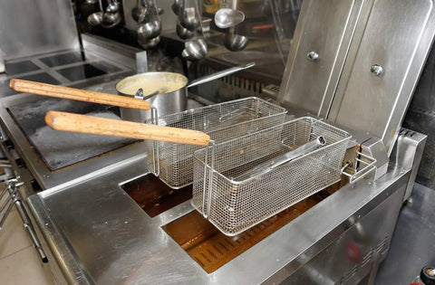 Deep Fryer Cleaning Brush 27 Inch Straight High Temp Commercial Kitchen Tool With Heavy Duty Brass Bristles Heat Resistant Up To 750 F Deep Fryer Cleaner Made In USA shown beside fryer baskets on a stainless steel deep fryer.