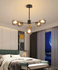 Six Light Glass Globe Sputnik Chandelier In Matte Black With Amber Shade illuminating a modern bedroom