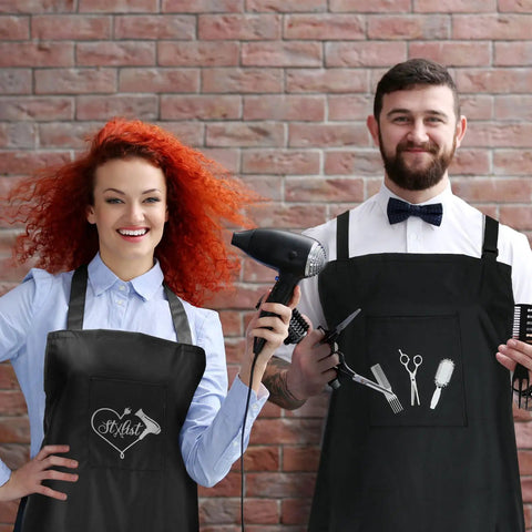 Two hairstylists wearing 4 Piece Waterproof Hair Stylist Apron Set With 4 Pockets Black 33X25 Inch Salon Aprons, holding tools.