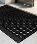 Heavy Duty Outdoor Doormat With All Weather Waterproof Construction Non Slip Drainage Entry Mat For Garage Home Pool Or Commercial Use Dirt Trapper Welcome Rug 17 By 29.5 Inches Black with visible drainage holes by an entryway.