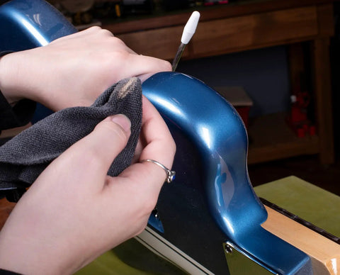 Cleaning an electric guitar body with a microfiber cloth using the Complete Guitar Care Kit And Clean Polish Set With Fretboard Conditioner.