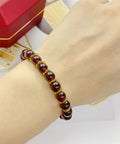 Person wearing bracelet with red beads, accented by 120 Pcs Mini Crown Charms 3D Alloy King Crown Beads for jewelry making and crafts.