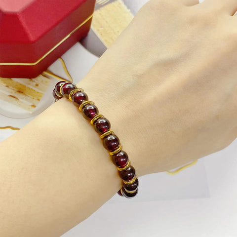 Person wearing bracelet with red beads, accented by 120 Pcs Mini Crown Charms 3D Alloy King Crown Beads for jewelry making and crafts.