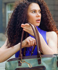 Woman with curly hair holding a stylish green handbag featuring a Heavy Duty Brass Double Ended Bolt Snap Hook.
