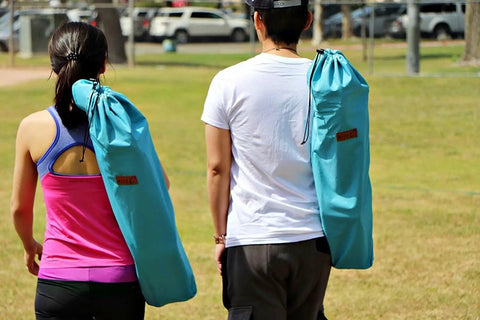 Two people carrying Low Profile Beach Chair 2 Pack For Adults Folding And Portable With Cup Holder And Carry Bag Perfect For Beach Boat River Sand Concerts Camping And Kids For Everyday Outdoor Fun And No Fuss Setup on their shoulders.