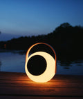 Eye Color Changing LED Lantern With 10W Bluetooth Speaker, White Mood Lamp for outdoors by riverside at dusk.
