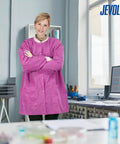 Woman wearing pink 50 pack disposable lab coats for adults hip length with pockets and knit cuffs 45gsm SMS multi layer fabric.