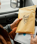 Person holding Kraft Bubble Mailers 8.5x12 Self Sealing Padding Envelopes 25 Pack Cushioned Shipping Bags in a car