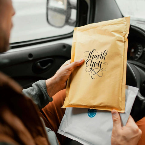 Person holding Kraft Bubble Mailers 8.5x12 Self Sealing Padding Envelopes 25 Pack Cushioned Shipping Bags in a car