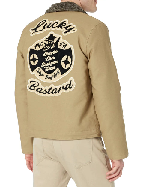 Back view of N1 Deck Lucky Bastard Denim Jacket With Vintage Acid Wash In Tan Color, showcasing large embroidered patch.