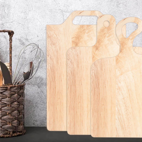 Four light wood charcuterie and cutting boards with handles standing upright against a wall next to a wicker basket with utensils.