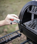 Hand installing Lid Clamp Replacement For Longhorn And Highland Smokers, 1 Pack on offset grill firebox.