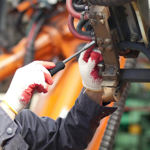 Person using screwdriver on machinery part in industrial setting