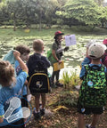 Children observing nature with teacher next to pond, potential educational use for 24 Pack Handheld Magnifiers With 5X And 15X Lenses.