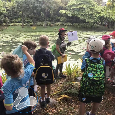 Children observing nature with teacher next to pond, potential educational use for 24 Pack Handheld Magnifiers With 5X And 15X Lenses.