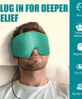 Ultra Soft Heated Eye Mask With Adjustable Warmth For Dry Eyes And Puffy Eyelids Fast Relief For Sinus Pressure And Tension Headaches Hits Different Premium Silk Touch Fits Snug Real Good Restorative Warmth Chill Vibe worn by a man with a plugged in cord.