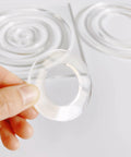 Close-up of a hand holding a clear acrylic ring from the Slick Multi Circle Router Jig For Pro Woodworkers And Craft Pros.