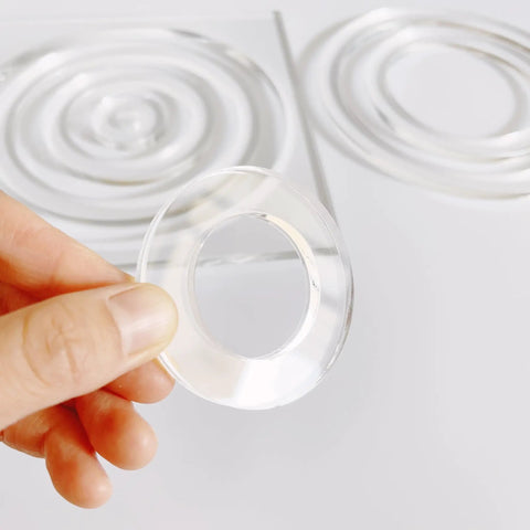 Close-up of a hand holding a clear acrylic ring from the Slick Multi Circle Router Jig For Pro Woodworkers And Craft Pros.