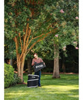 Man using Badass 40V Cordless Backpack Leaf Blower With Brushless Motor in yard, clearing debris with a RYOBI bag.