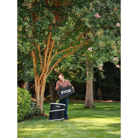 Man using Badass 40V Cordless Backpack Leaf Blower With Brushless Motor in yard, clearing debris with a RYOBI bag.