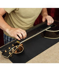 Person using All In One Guitar Repair Kit With Neck Rest Cradle And Pro Grade Gig Ready Work Mat for instrument maintenance.